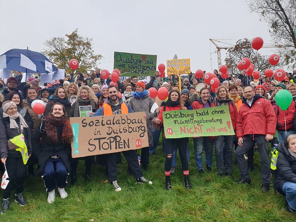 Mitarbeiter*innen des DRK Duisburg protestieren gegen die Kürzungen Mitarbeiter*innen des DRK Duisburg halten Plakate für die Demonstration hoch